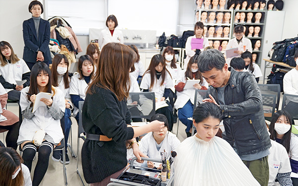 学生たちを前にプロがヘアセットの講義をおこなう様子