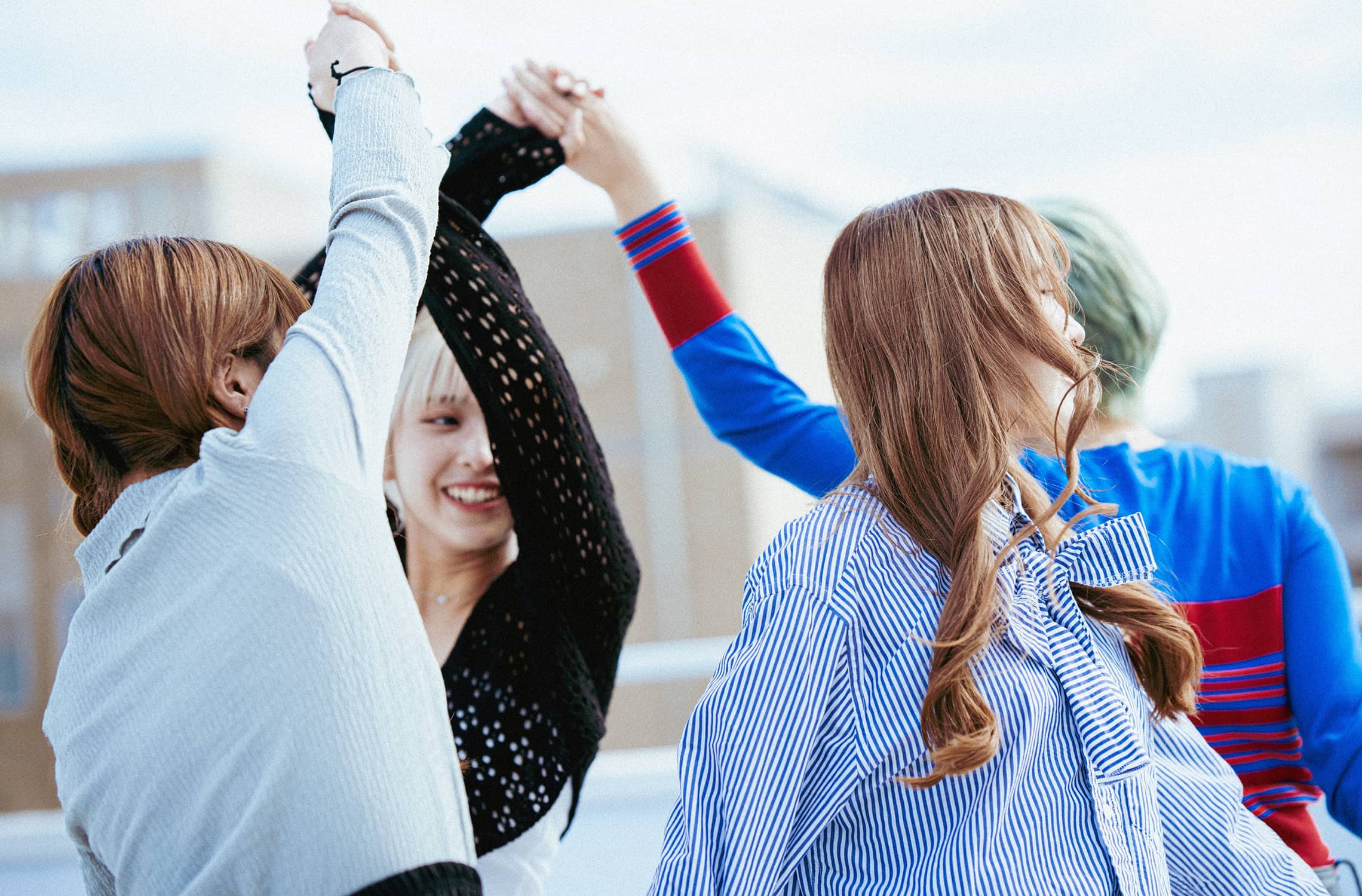 屋上で手を繋いで回る笑顔の女子学生たち